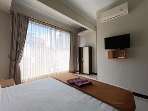 The Cabin Hotel Ngupasan في يوغياكارتا: غرفة نوم بسرير ونافذة كبيرة