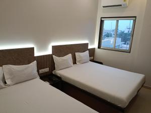 two beds in a small room with a window at Hotel Ritz Vesu - Hotels in Vesu, Surat in Surat