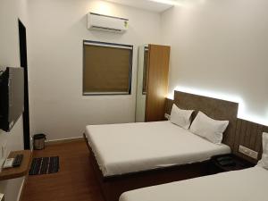 een hotelkamer met 2 bedden en een televisie bij Hotel Ritz Vesu - Hotels in Vesu, Surat in Surat