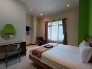 a bedroom with a bed and a desk and a window at The Cabin Hotel Ngupasan in Yogyakarta