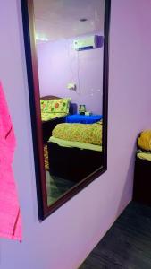 a mirror on a wall with a bed in a room at TEC Resort and bar in Dharān Bāzār
