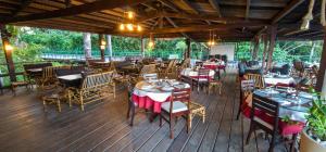 ein Restaurant mit Tischen und Stühlen auf einer Holzterrasse in der Unterkunft Hotel - Gran Lençóis 2 suítes in Barreirinhas