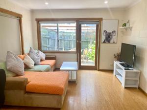 a living room with a couch and a tv at Cozy Hobart Garden Retreat in Sandy Bay