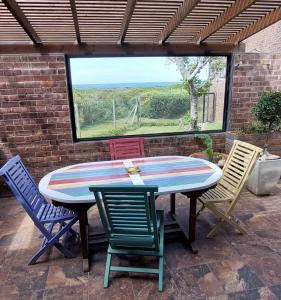 a patio table with four chairs and a window at The Amaryllis Luxury Apartment Bella Donna in Bettyʼs Bay