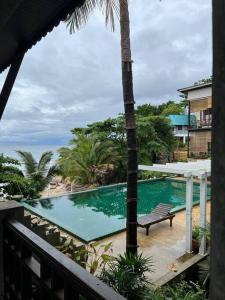 a swimming pool with a bench and a palm tree at Seafront Jungle Bungalow in Koh Phangan