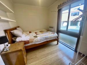 a small bedroom with a bed and a large window at Cozy Hobart Garden Retreat in Sandy Bay