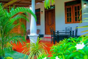 a house with a porch with a white pillar and plants at Chanaka Holiday Inn in Sigiriya
