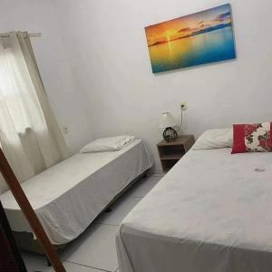 a bedroom with two beds and a picture on the wall at Rochedo Casa de Praia in Nova Viçosa