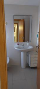 ein weißes Badezimmer mit einem Waschbecken und einem Spiegel in der Unterkunft Apartamento a 100 metros del mar in Piles