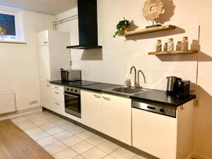 a kitchen with white cabinets and black counter tops at Appartement Bloem in Zandvoort