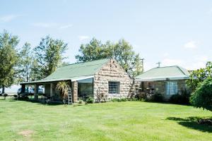 una casa in pietra con tetto verde e cortile di The Border Post, Bed and Breakfast a Bergville