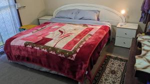 una camera da letto con un letto con una coperta rossa di BIDWILL GARDENS ON MIDDLETON - Private Room King-Size Bed or Open Lounge Room Floor Mattress SHARED Bathroom FREE Kitchen Essentials FREE Laundry Facilities Fast NBN WIFI HDTV NETFLIX, YOUTUBE, KAYO Private Transport and Meal Services Available On Request a Bidwill