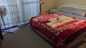 una camera da letto con un letto con una trapunta sopra di BIDWILL GARDENS ON MIDDLETON - Private Room King-Size Bed or Open Lounge Room Floor Mattress SHARED Bathroom FREE Kitchen Essentials FREE Laundry Facilities Fast NBN WIFI HDTV NETFLIX, YOUTUBE, KAYO Private Transport and Meal Services Available On Request a Bidwill