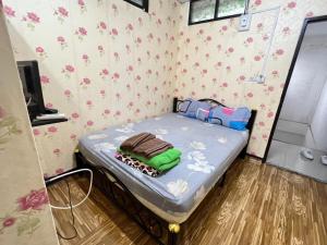 uma pequena cama num quarto com flores na parede em Natcha Place Rangsit Donmuang em Ban Talat Rangsit