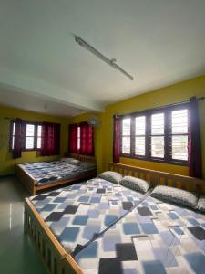 two large beds in a room with windows at Ganapathy Homes valparai in Vālpārai