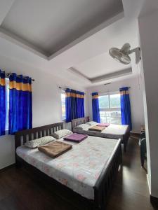 two beds in a room with blue curtains at Ganapathy Homes valparai in Vālpārai