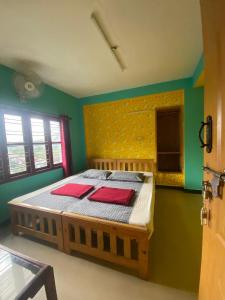a bedroom with a bed with red pillows on it at Ganapathy Homes valparai in Vālpārai