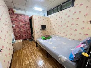 a small room with a bed and a wall with flowers at Natcha Place Rangsit Donmuang in Ban Talat Rangsit