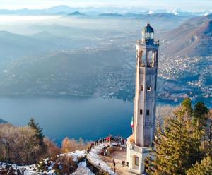 a clock tower on top of a mountain with a body of water at vigne 5 in Brunate