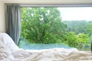 a bed in front of a window with a tree at Tinyhouse Minimalus Panorama Schlafloft im Grünen in Dessighofen