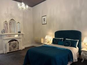 a bedroom with a blue bed and a fireplace at Convent at Koroit in Koroit