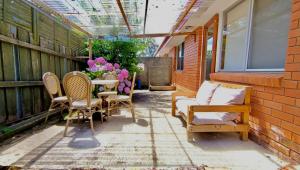 een patio met stoelen, een tafel en bloemen bij Cozy Hobart Garden Retreat in Sandy Bay