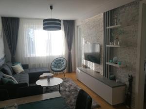 a living room with a couch and a tv at Apartman Kaja (ski-to-door, Jahorina) in Jahorina