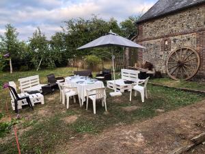 a table and chairs with an umbrella in a yard at Charmante maison au calme avec jardin, wifi, idéale pour les familles in Sainte-Gauburge-Sainte-Colombe