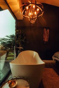 a bathroom with a bath tub and a chandelier at The Wellsprings Lodges and Restaurant in Clitheroe