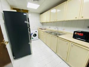 cocina con nevera negra y microondas en BAITH AL JANNAH LLC Vacation home Rentals, en Abu Dabi