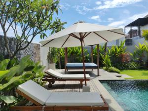 um pátio com um guarda-sol e cadeiras e uma piscina em Villa Naga Hoki em Munggu