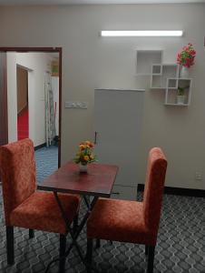 a table with two chairs and a table with flowers on it at Hotel In Need - Near to the US and Canada Embassy in Dhaka in Dhaka