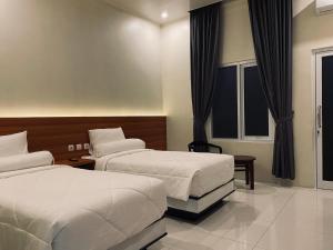 a hotel room with two beds and a window at Genio Syariah Hotel Solo in Tjolomadu