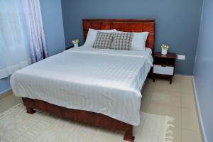 a bedroom with a large bed with a wooden headboard at Pearl Sanctuary 01 Kiwatule, Kampala in Kira