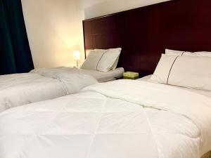 2 camas en una habitación de hotel con sábanas blancas en Saraya Al Joude, en Irbid