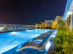 - une piscine de l'hôtel avec des chaises longues la nuit dans l'établissement YK Home - The Song Apartment, à Vung Tau