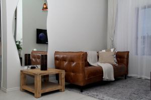 un sofá de cuero marrón en una sala de estar con mesa en Urbane- By LaSerene -Carlswald, en Midrand
