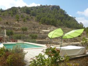 a pool with two green umbrellas next to a mountain at Guest House Guapas in La Garapacha