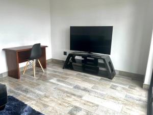 a living room with a flat screen tv and a desk at 14 on Lawrence in Durban