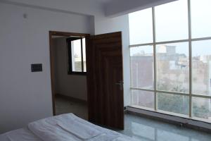 een slaapkamer met een deur, een raam en een bed bij The Dharams Hotel in Lucknow