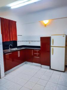 a kitchen with red cabinets and a white refrigerator at Alor Elite Flats in Calangute