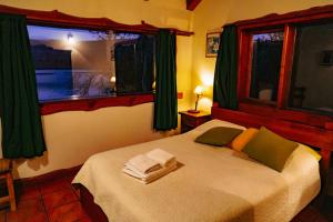 a bedroom with a bed with green curtains and a window at CABAÑAS SOLO POR HOY in Villa Pehuenia