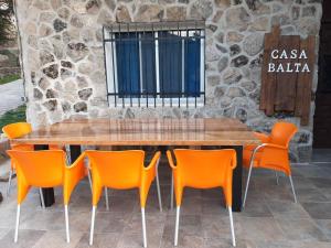 una mesa de madera con sillas naranjas frente a un edificio en Casa Balta, en Ávila