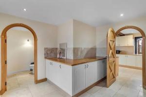 a kitchen with white cabinets and an open door at amazing barn conversion with hot tub in North Walsham