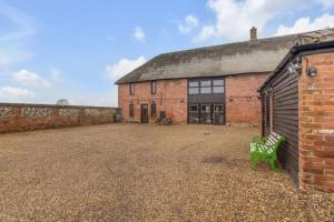 a brick building with a green bench in front of it at amazing barn conversion with hot tub in North Walsham