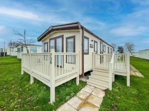 a tiny house with a porch and a staircase at Beautiful 6 Berth Caravan With Decking At Valley Farm Holiday Park Ref 46736v in Great Clacton