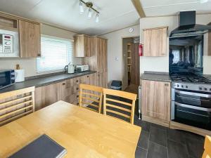 uma cozinha com uma mesa de madeira e um fogão forno superior em Beautiful 6 Berth Caravan With Decking At Valley Farm Holiday Park Ref 46736v em Great Clacton