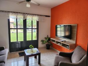 uma sala de estar com paredes cor de laranja e uma televisão de ecrã plano em Casa Andar Térreo - Balneário Nordeste - Imbé - RS em Imbé