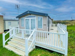 a small house with a white railing and a porch at Beautiful Caravan With Decking At Naze Marine Park, Sleeps 8 Ref 17341br in Walton-on-the-Naze