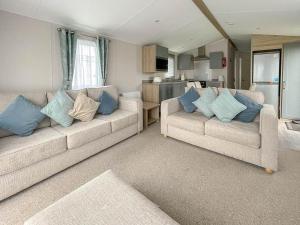 a living room with two couches and blue pillows at Beautiful 8 Berth Caravan With Decking At Naze Marine Park, Essex Ref 17184p in Walton-on-the-Naze